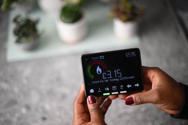 A person holding a smart energy meter by a table.