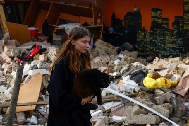 A resident carries a cat at the site of a house heavily damaged by a Russian drone strike, amid Russia's attack on Ukraine, outside of Kyiv, Ukraine May 18, 2025. REUTERS/Valentyn Ogirenko TPX IMAGES OF THE DAY